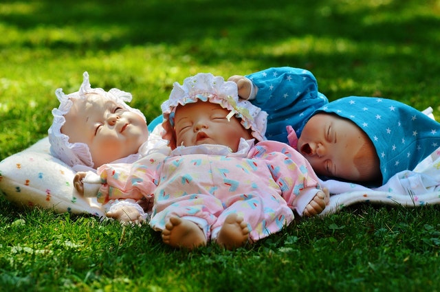 Tři panenky položené na trávě